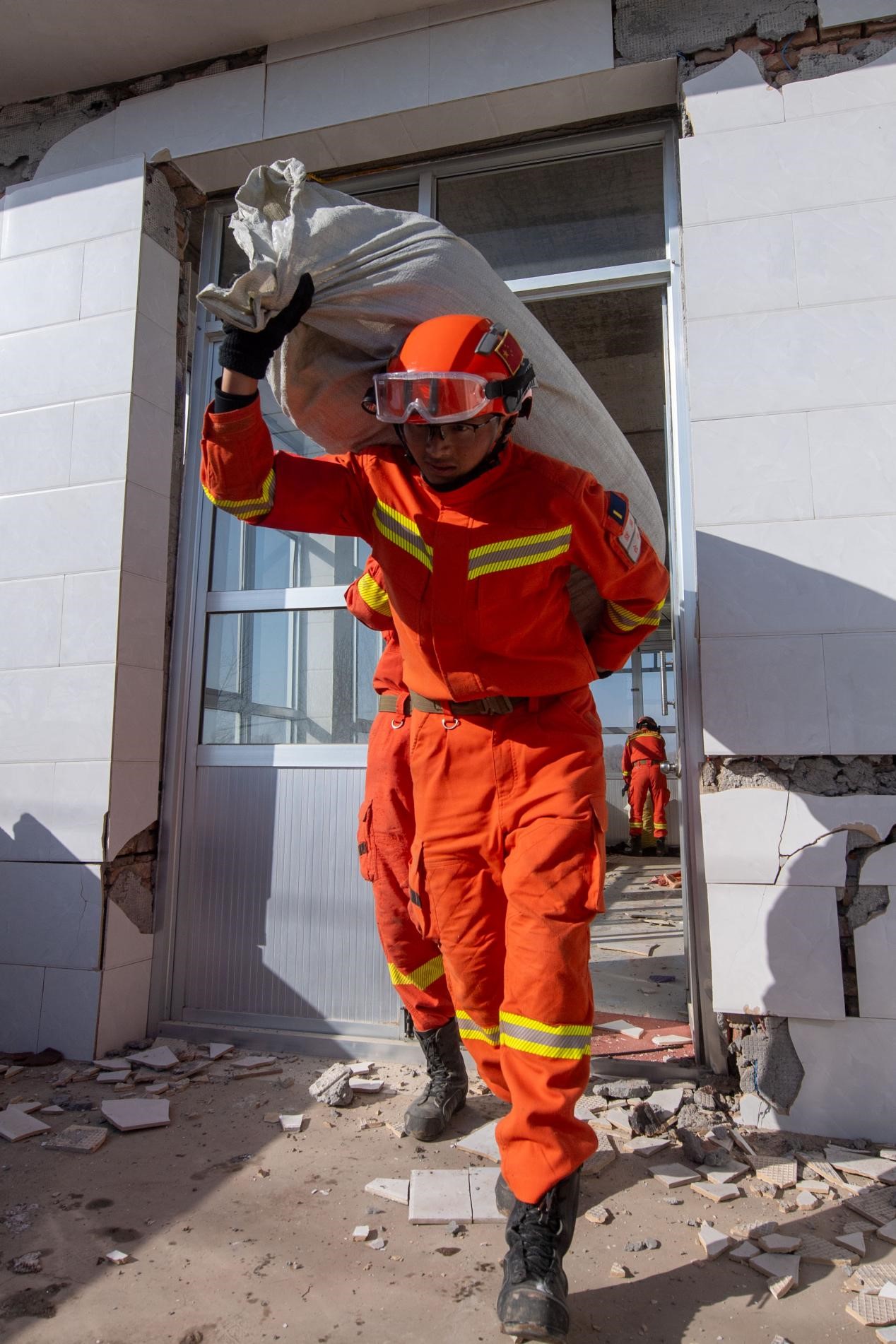 12月21日,在积石山县石塬镇石塬村,消防救援人员正在帮助群众转运物资。人民网记者 翁奇羽摄